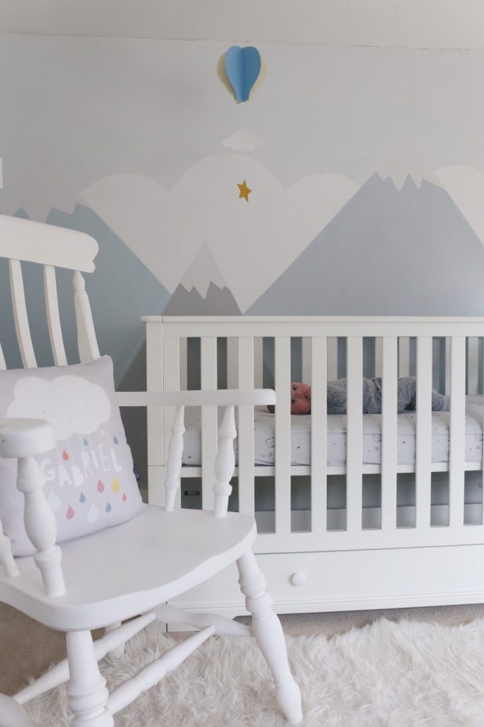 Image of the cot bed in a nursery next to a nursing chair.