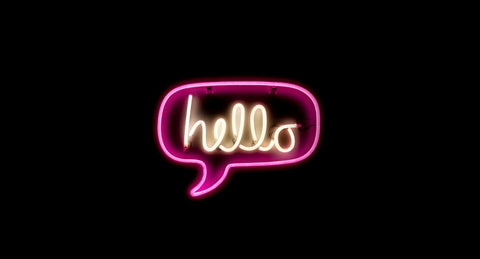 An illuminated sign that is pink and in the shape of a speech bubble filled with the word hello.