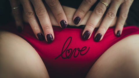 Close up frint view of woman wearing red underpants which have the word 'love' printed in black on the front.