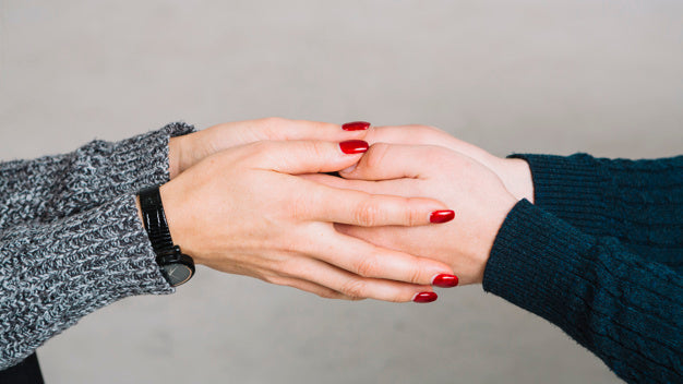 Cropped image of female psychologist holding her client's hands against gray backdrop Free Photo