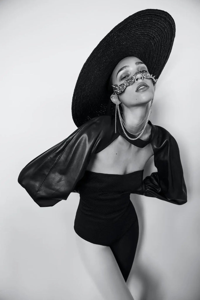 An elegant black and white shot by Erica Fava of a model wearing a wide hat paired with an intricate nose jewelry mask