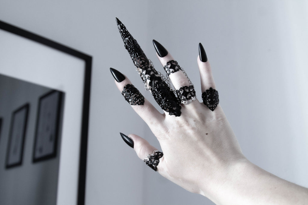 a set of 5 black filigree rings in gothic style worn one for each finger