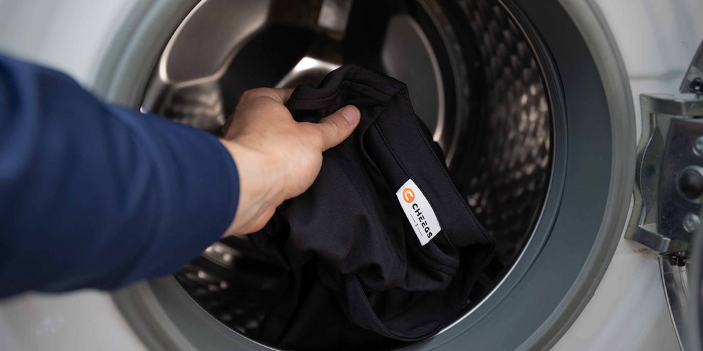 Man throwing a Cheegs Collarless Dress Shirt in the washing machine.