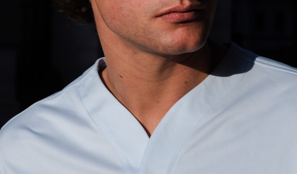 Close up of the neck of a man wearing a Cheegs collarless dress shirt in light blue