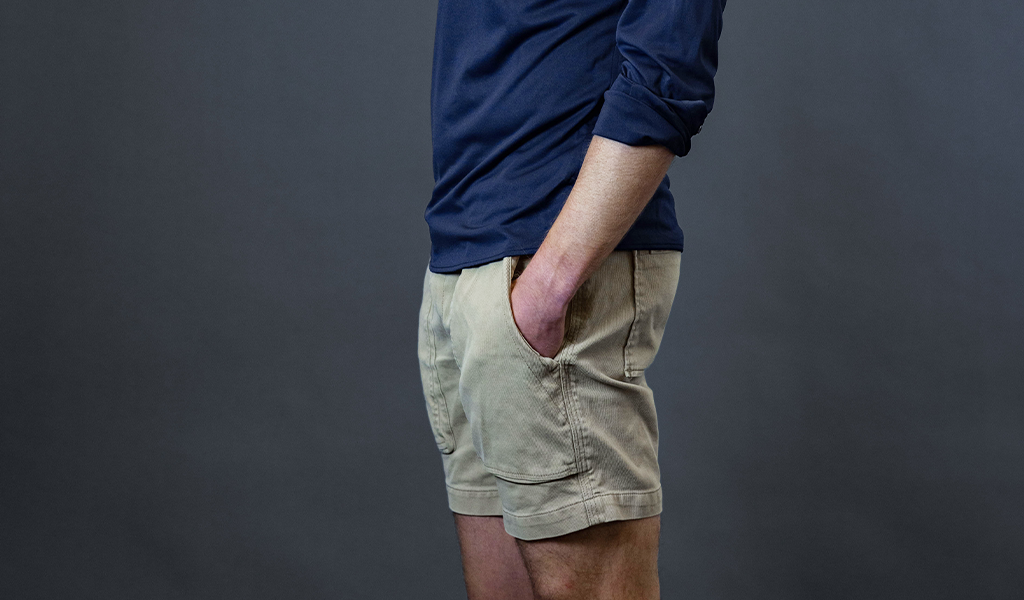 Man wearing a Cheegs Collarless Dress Shirt 2.0 Popover in Navy with beige shorts