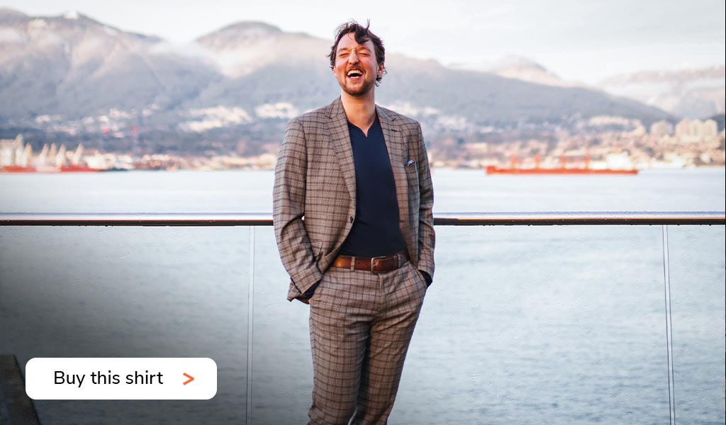 Smiling business man wearing a Cheegs collarless dress shirt in navy with a full checkered suit.