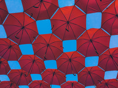 a collection of a bunch of red umbrellas open with a blue sky in the background