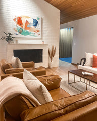 The Coziness Consultant_Photo of a living room with a camel colored couch and chairs with blankets and art