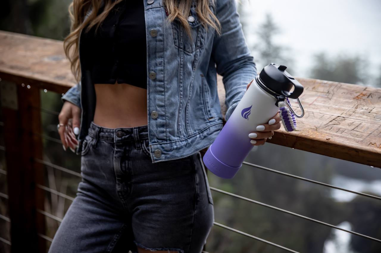 A woman leaning against a railing while holding a white and purple water bottle