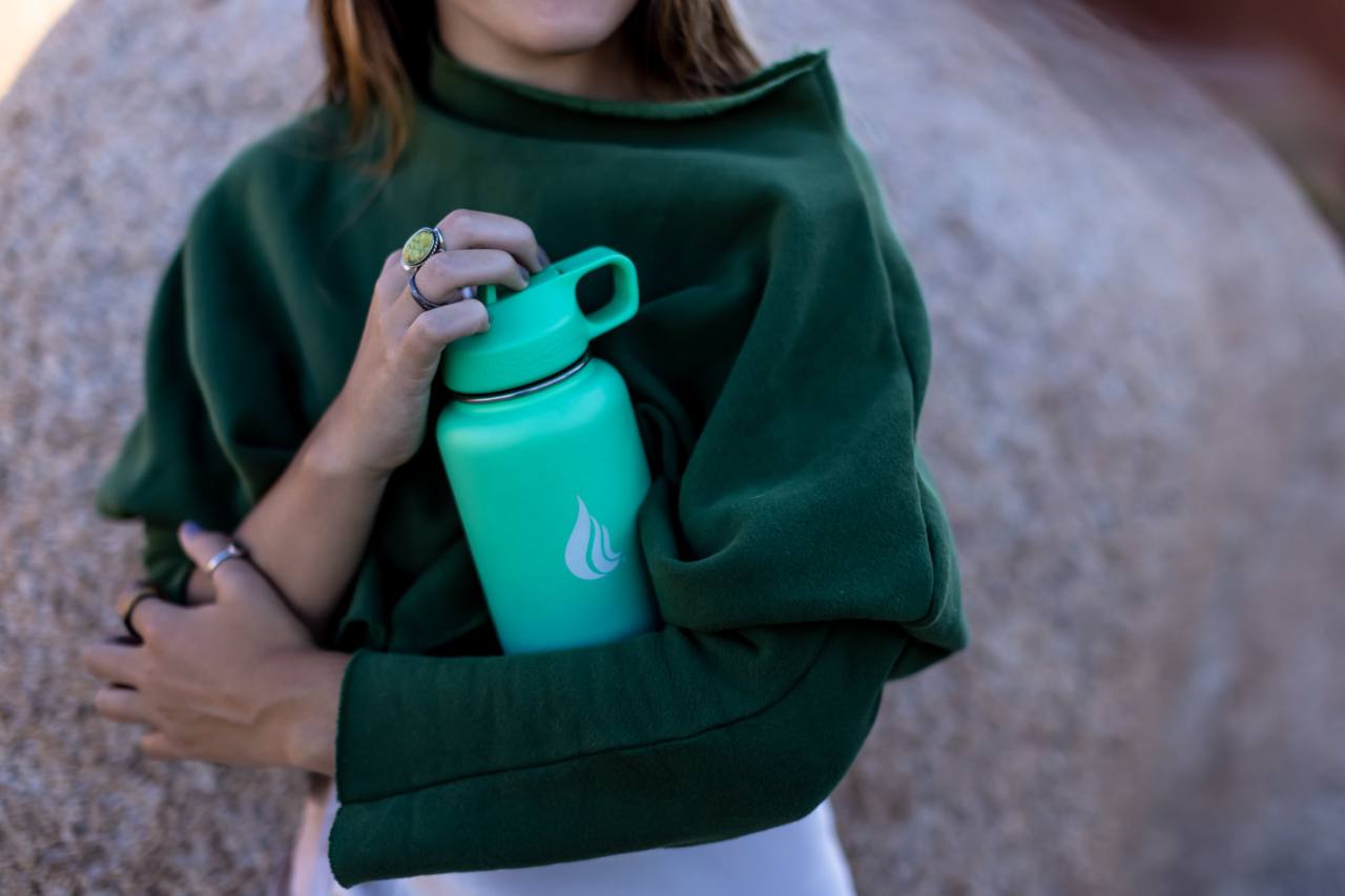Woman in green shirt hugging a stainless steel water bottle