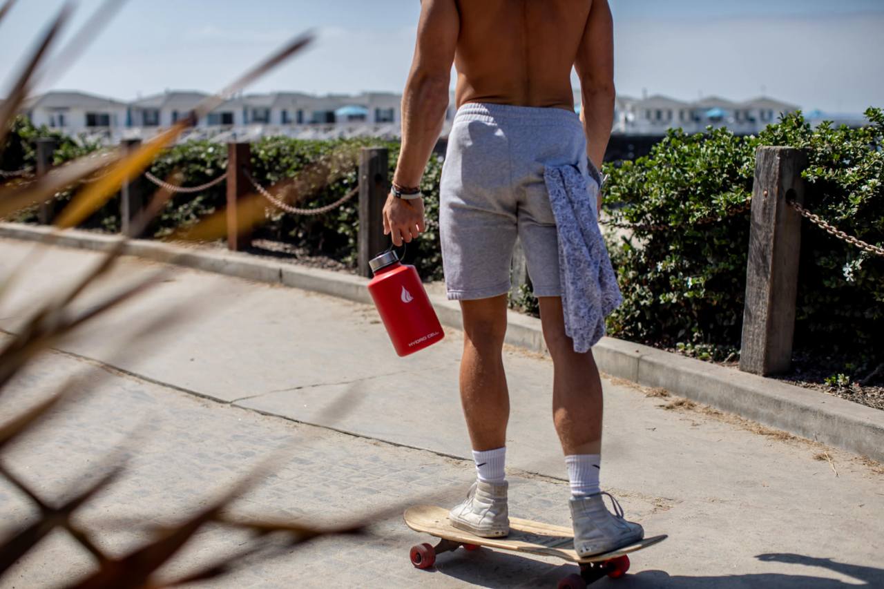 A man carrying a water bottle while standing on a skateboard