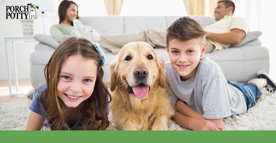 A couple sit on a couch while their two children lay on the floor with their Golden Retriever