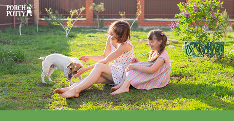 Two little girls play with their puppy in their back yard