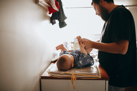 A Dad carefully changes his baby’s cloth nappy