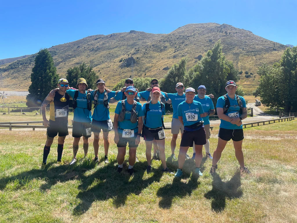 group of runner sin blue shirts in front of a mountain