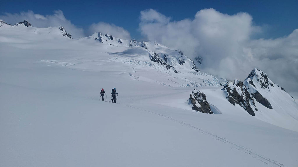 Two people skiing on a mountain surrounded by snow