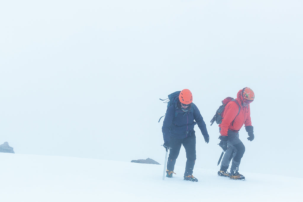 two people at the top of a mountain in the snow