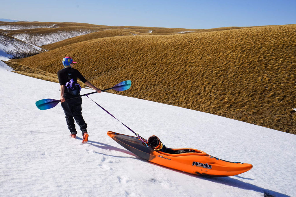Woman pulling her kayak on the snow