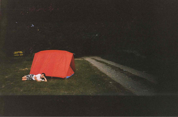 Girl lying in front a red tent