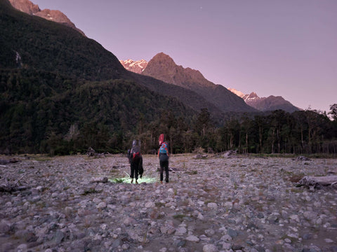 walking a river bed at sunrise with mountains in the background