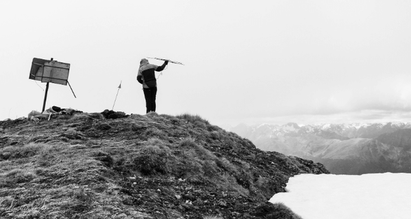 Woman standing on Miller Peak listening for Kea with an antenna.