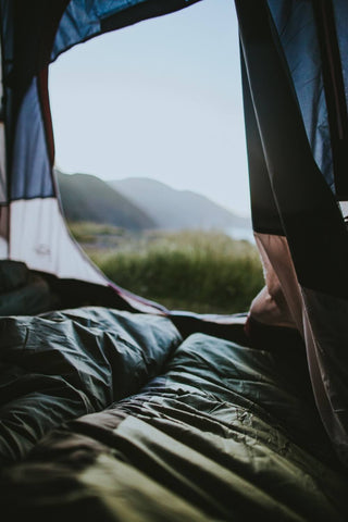 The view of a sleeping bag looking out into the grass and mountains