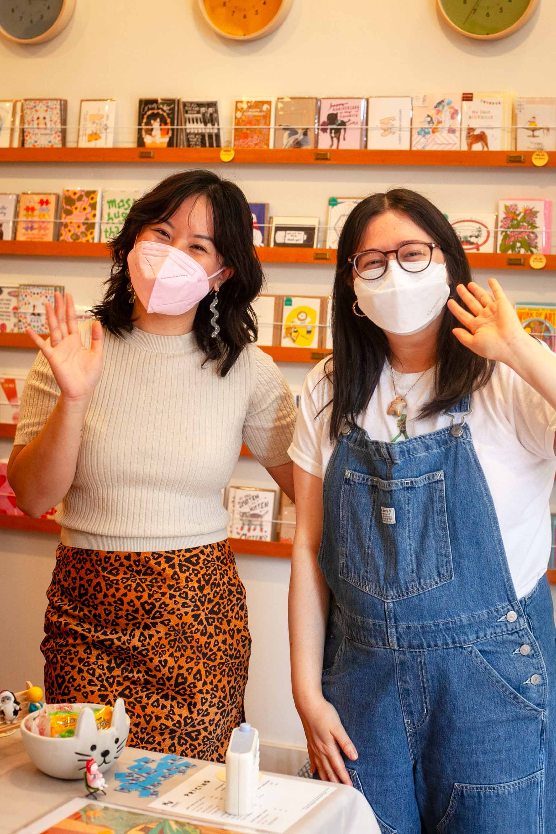 Happy First Friday! Hannah and Liz K, wearing masks, wave hello to our store photog.
