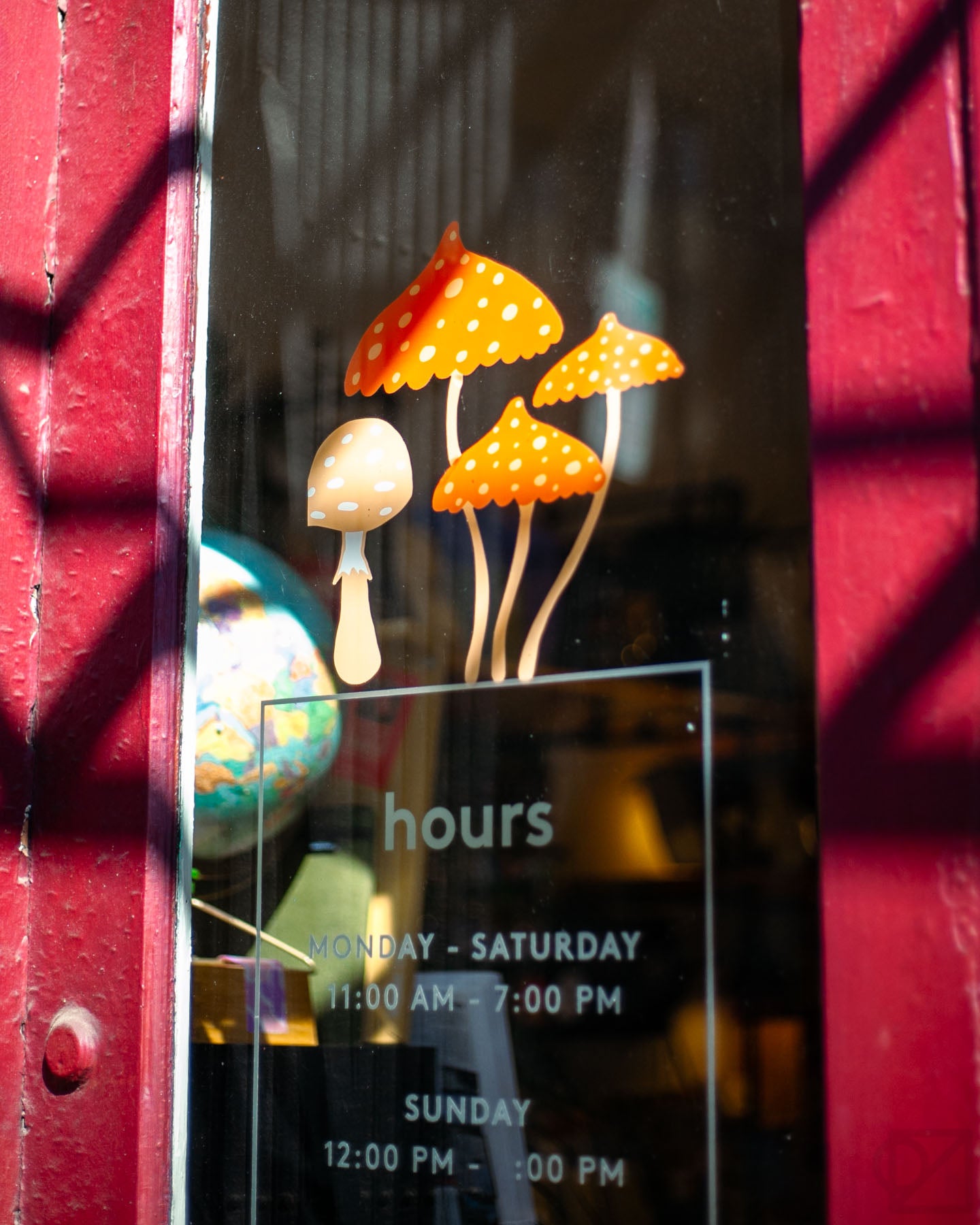 Madeleine Conover artwork for Omoi's front window features mushrooms of all kinds, plus plants and fuzzy friends