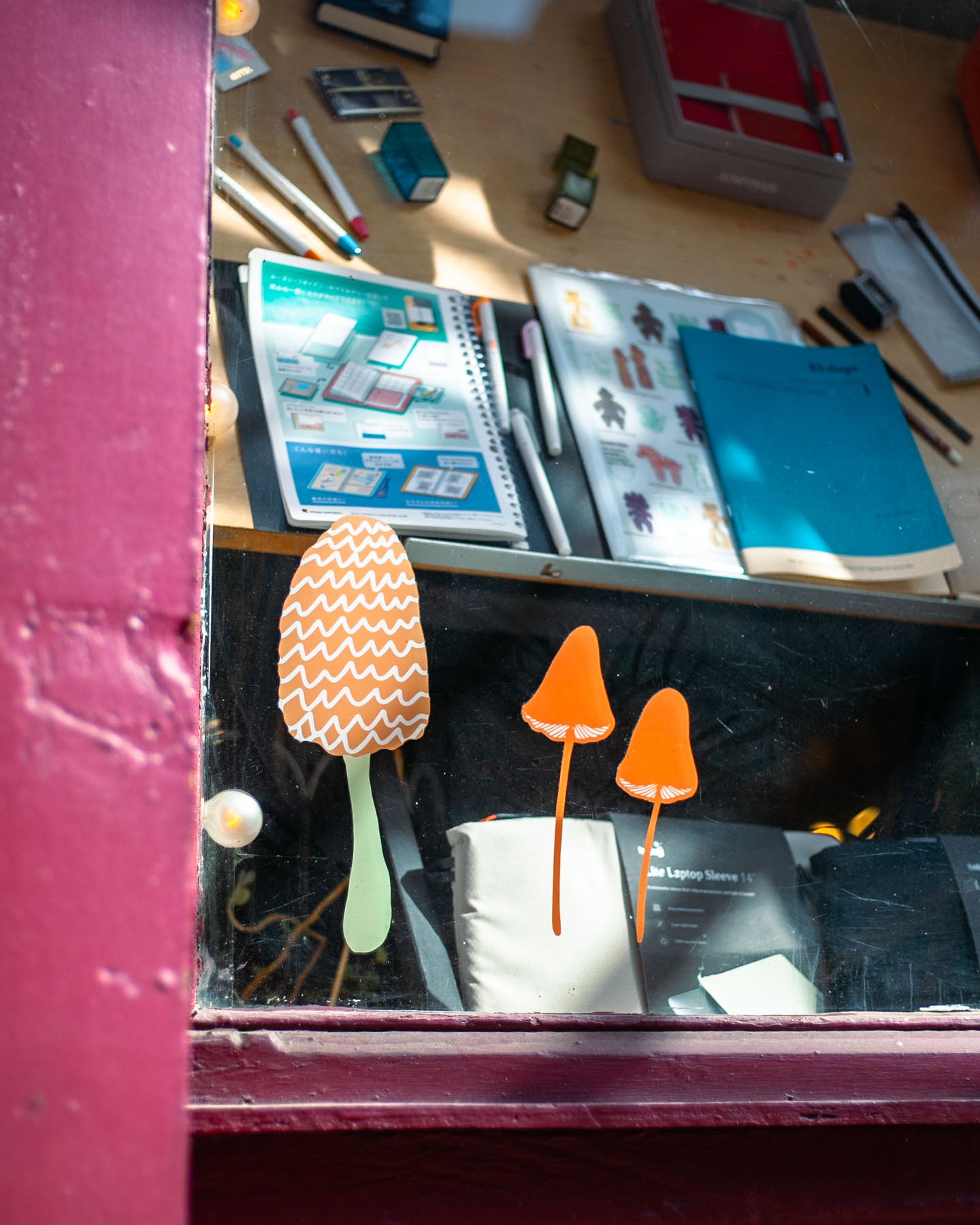 Madeleine Conover artwork for Omoi's front window features mushrooms of all kinds, plus plants and fuzzy friends