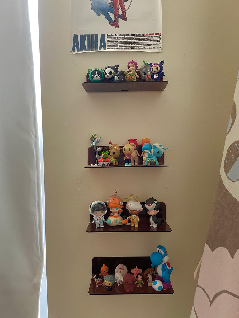 A picture of small cute plastic figurines on small wall mounted shelves.