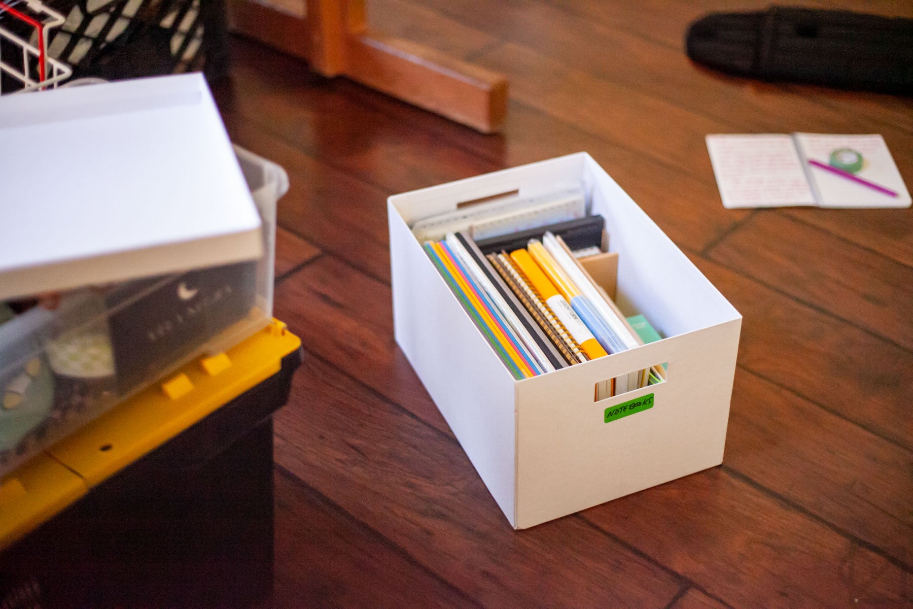 A filing box labeled Notebooks sits on the floor, with other boxes around it.