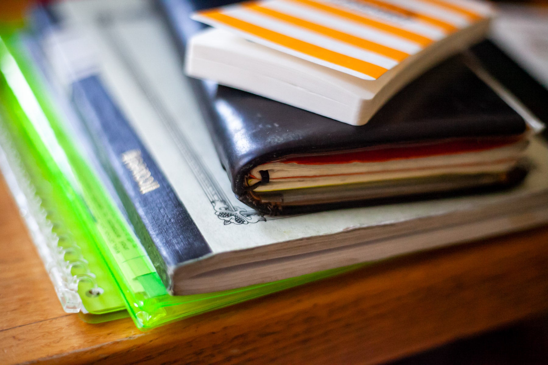 A close-up of the spines of several notebooks on a wood table