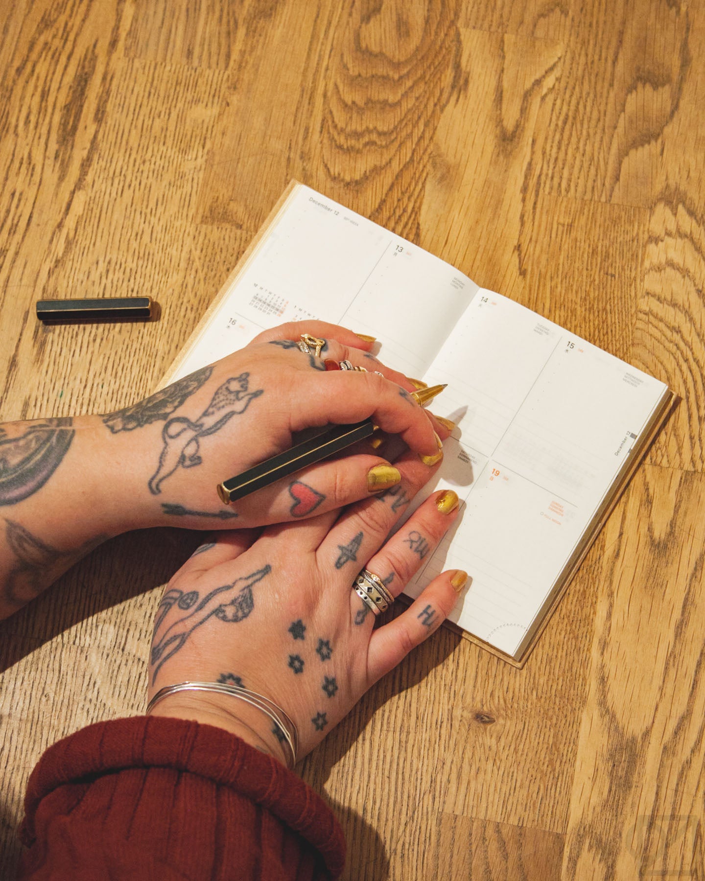Alexandra has tattooed hands, golden nails, and lots of jewelry that matches the golden theme of her planner