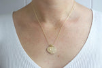 Load image into Gallery viewer, Model wearing AW Boutique&#39;s dual zodiac coin necklace featuring a dainty necklace chain, zodiac rustic coin charm, and your chosen star sign coin charm. Charms separated by a gold bead. Part of the Celestial Collection. Gold filled jewellery. Option shown is Taurus.
