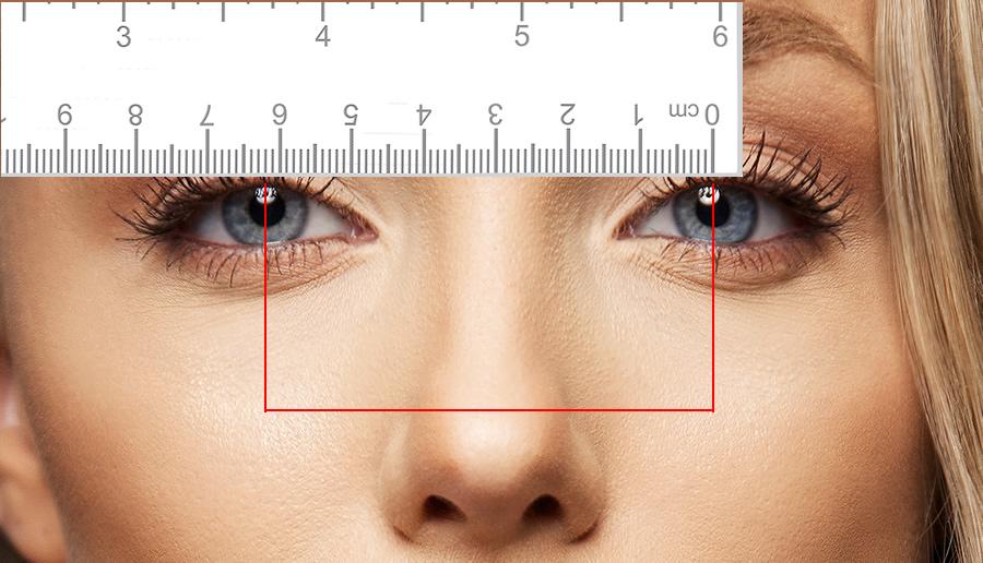 A woman whose Pupillary distance is being measured with a ruler in front of her eyes