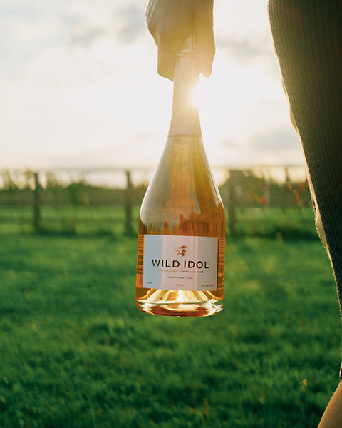 Person carrying Wild Idol non alcoholic wine in a field