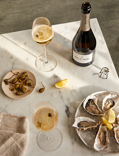 Glasses of Wild Idol Alcohol Free Sparkling White Wine on a table with Oysters and Olives