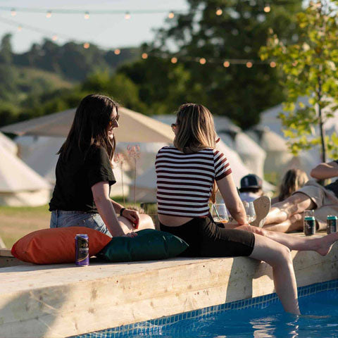 Festival goers sitting by a pool at Spook X Pop-Up Hotel, one of the glamping hotspots that serves Wild Idol's non alcoholic sparkling wines
