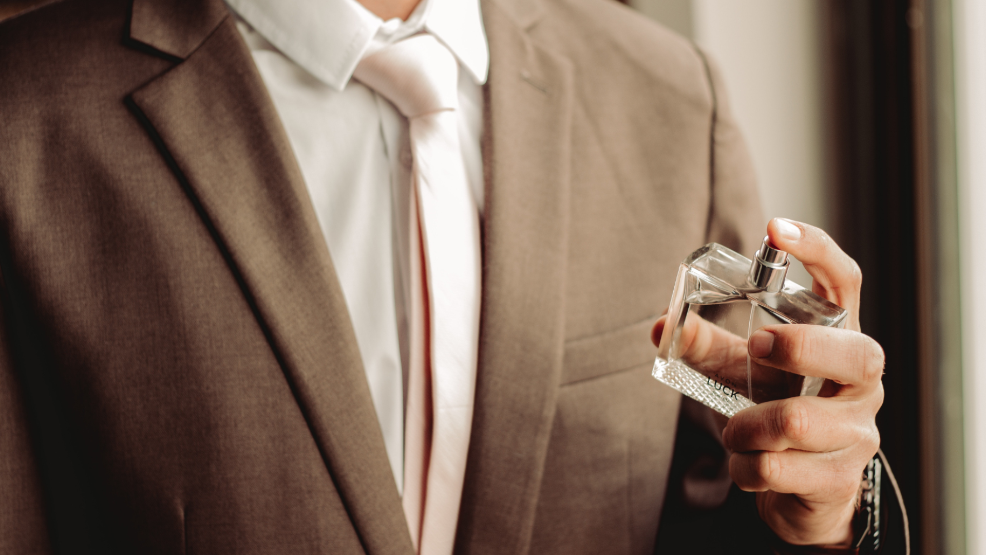 Man spraying cologne on himself. 