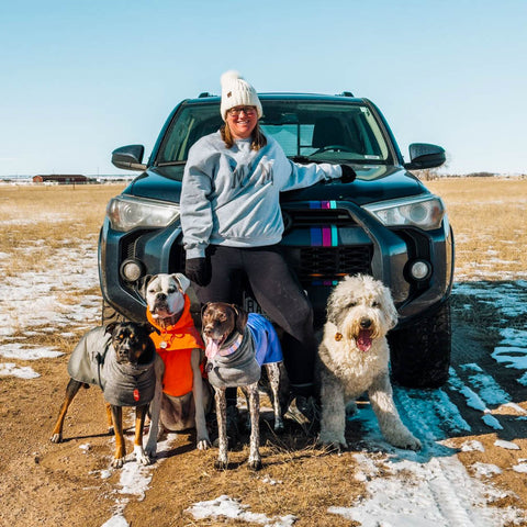 Woman with four dogs standing beside a Toyota 4runner traveling with her dogs