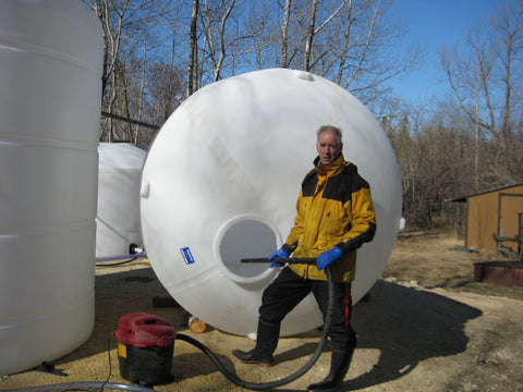 Rory Hart, co-owner of The Canadian Birch Company poses in springtimebeside a massive holding tank which captures the purified water, a by-product of the Birch sap concentration process.