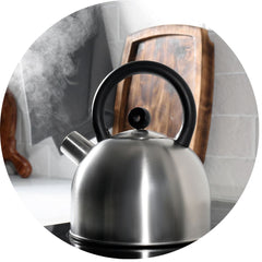 kettle boiling on a stove in a modern kitchen, steam pouring out of the spout.