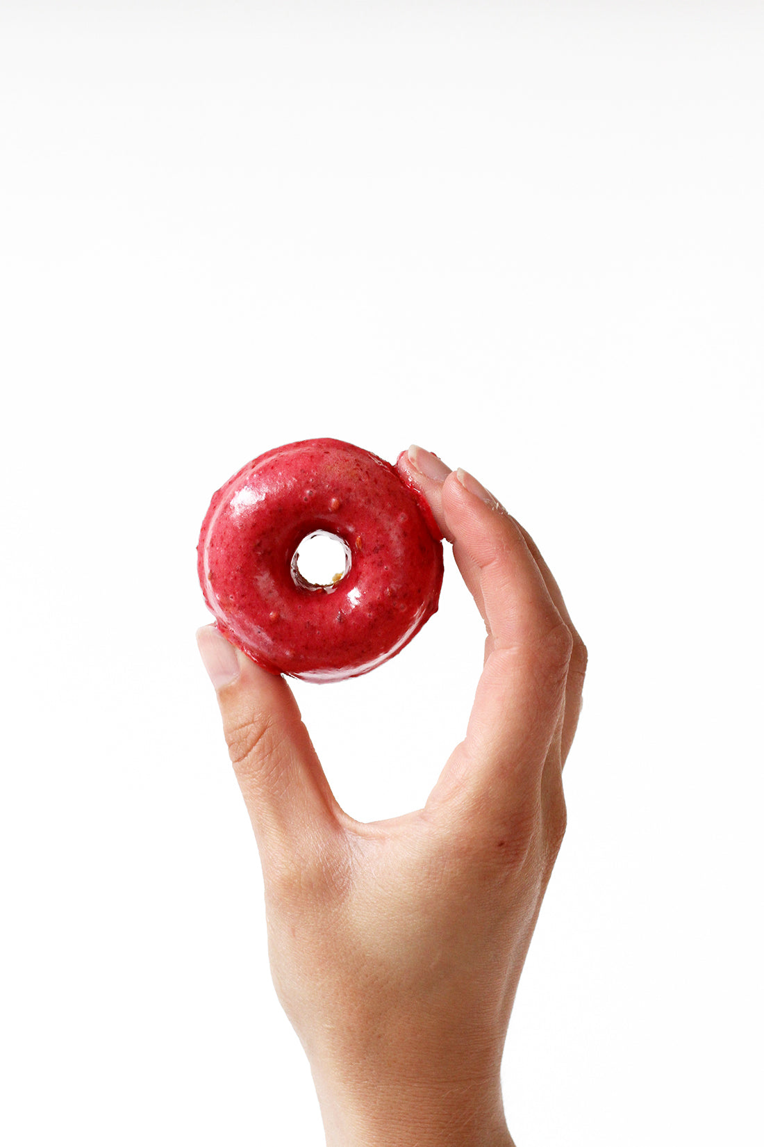 Image of a hand holding up one finished Miss Jones Baking Co Blackberry Buttermilk Donut