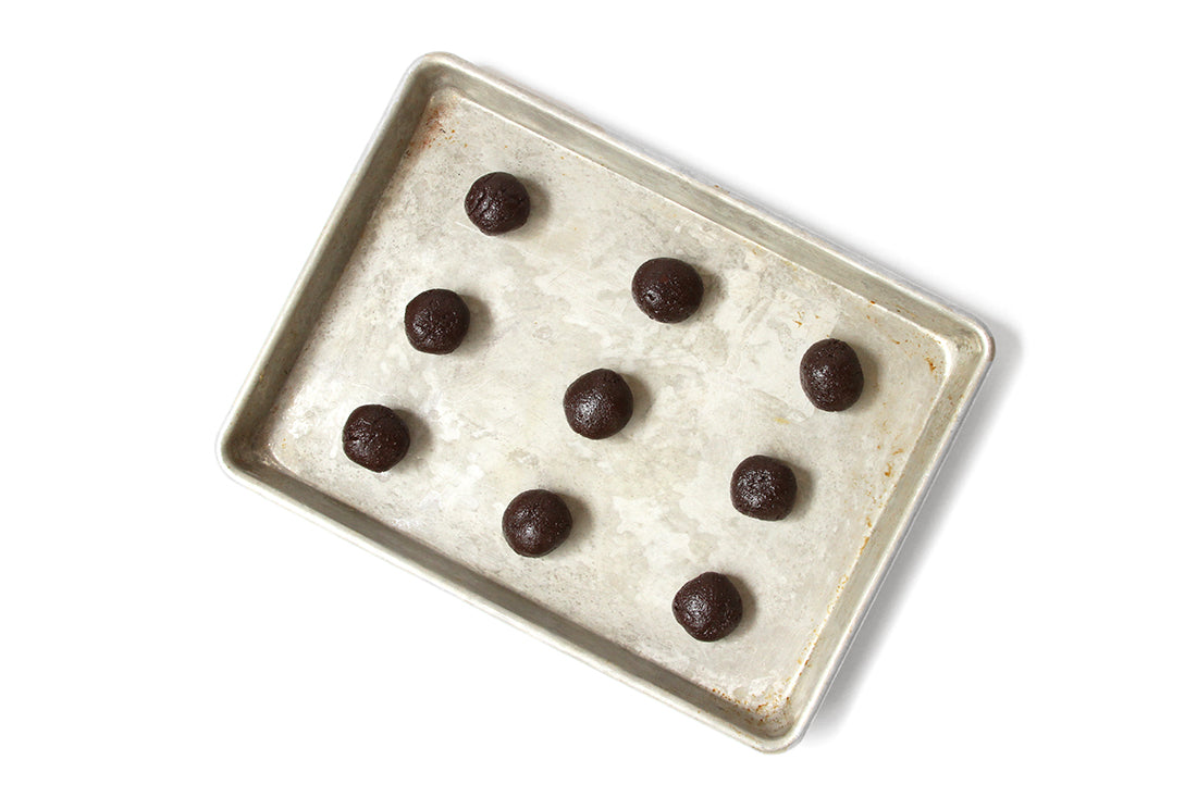 Image from above of nine Miss Jones Baking Co Brownie Batter Crinkle Cookie Sandwich dough balls on baking sheet