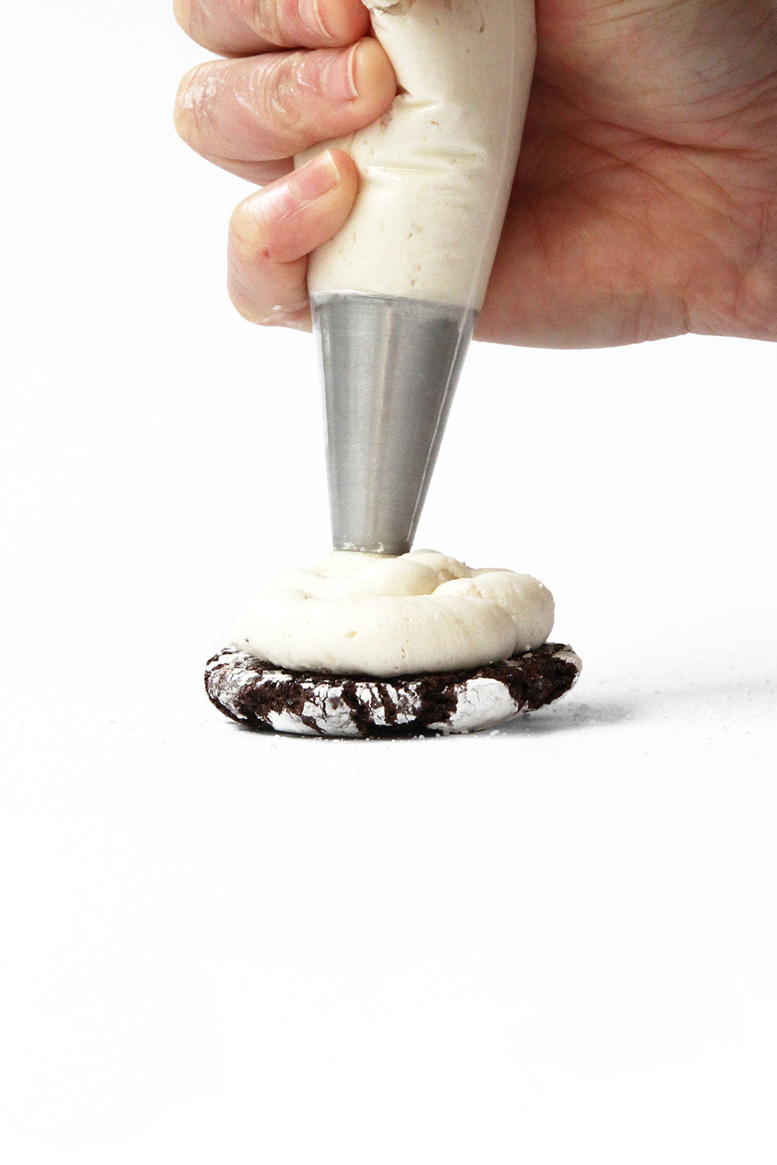 Close up image of a Miss Jones Baking Co Brownie Batter Crinkle Cookie being frosted