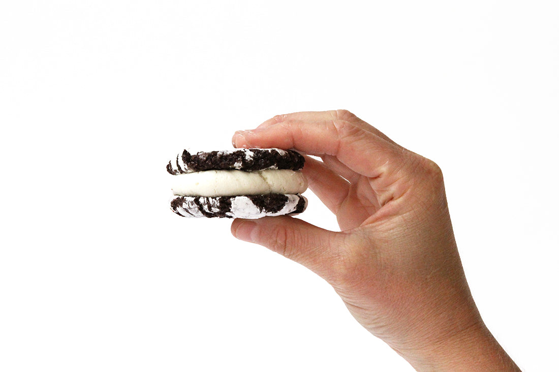 Image of side of hand holding a Miss Jones Baking Co Brownie Batter Crinkle Cookie Sandwich