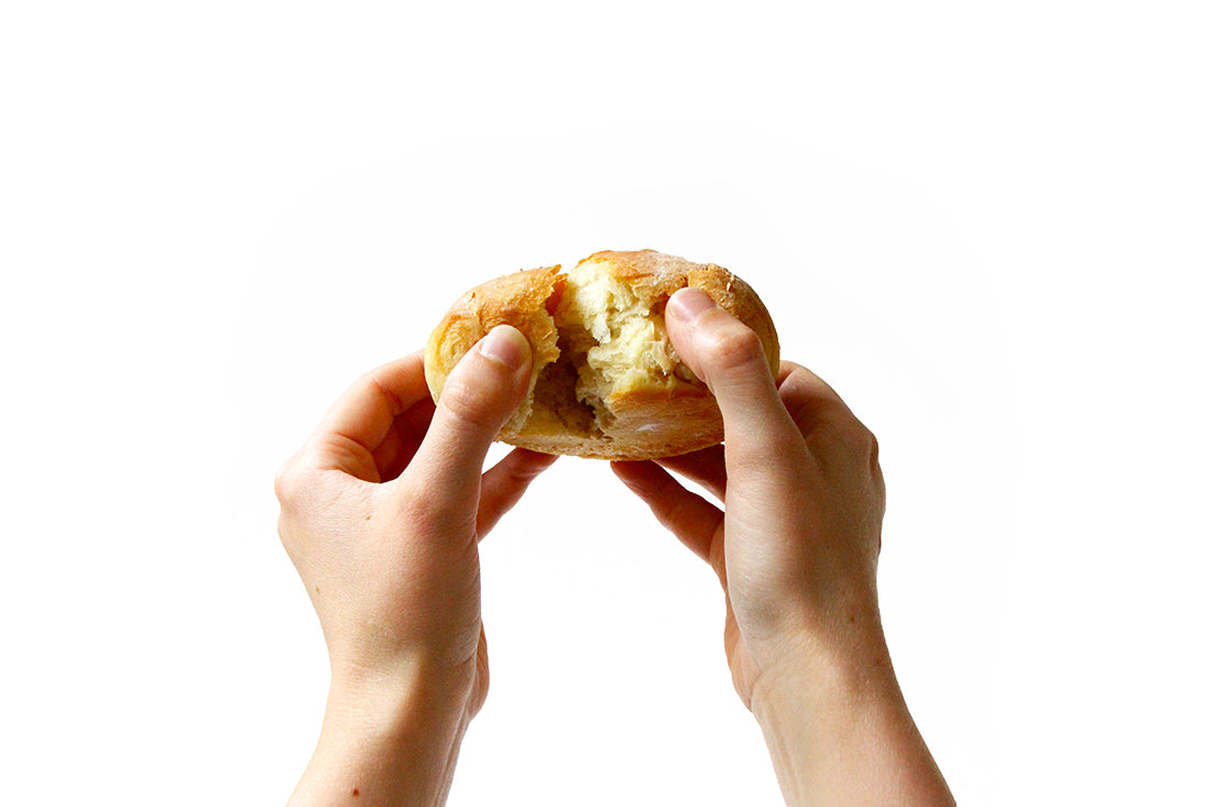 Image of hands breaking apart a Miss Jones Baking Co Cake mix Dinner Roll