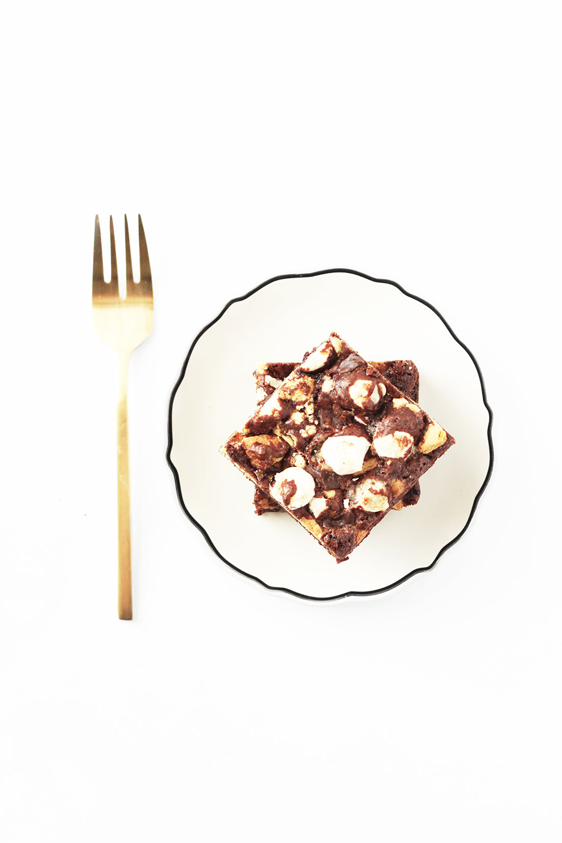 Image of two Miss Jones Baking Co Campfire Smores Brownies stacked on a plate next to a golden fork