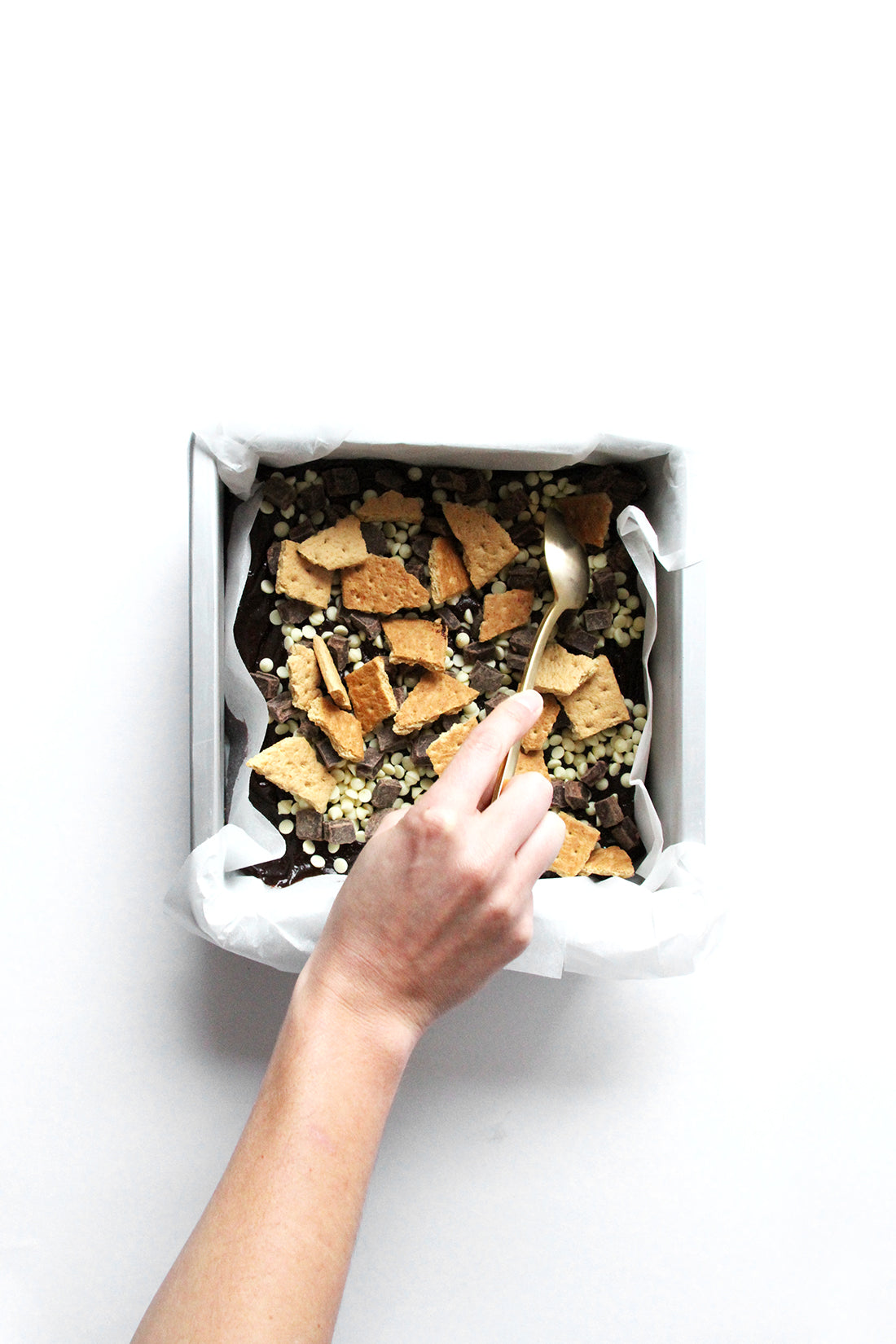 Image of Miss Jones Baking Co Campfire Smores Brownies in baking pan being topped with graham crackers