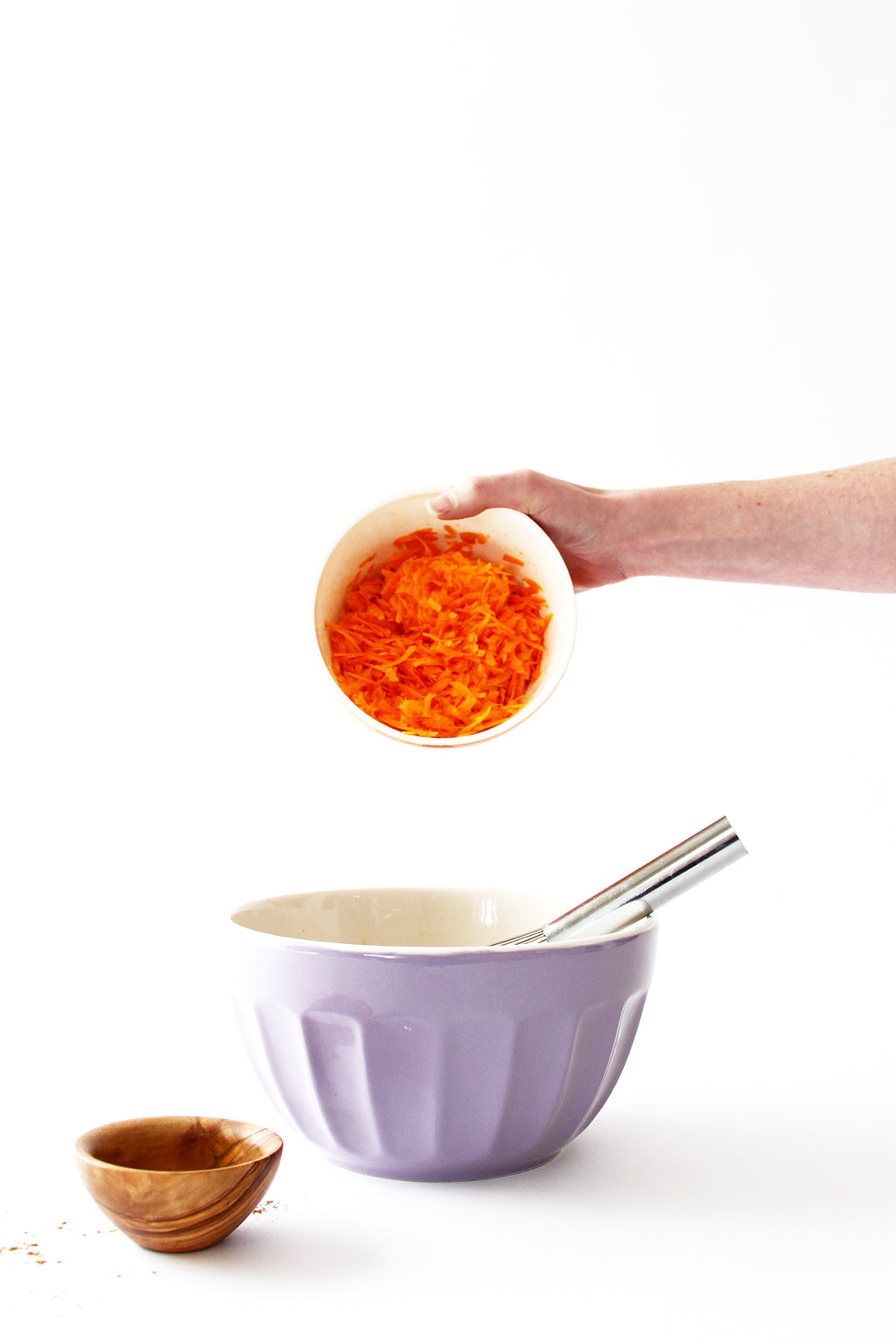 Image of shredded carrots being poured into a purple mixing bowl for Miss Jones Baking Co Carrot Spice Cake recipe